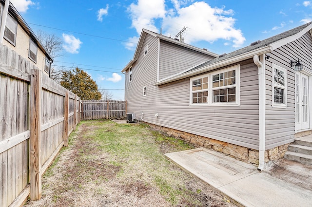 view of property exterior with central AC unit, a lawn, and a fenced backyard