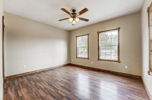 empty room featuring visible vents, baseboards, a ceiling fan, and dark wood-style flooring