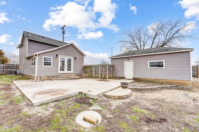 rear view of property with fence, central AC unit, french doors, a patio area, and an outbuilding