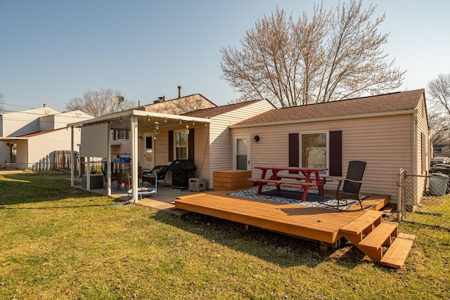 rear view of house featuring a yard, fence, roof with shingles, and a wooden deck