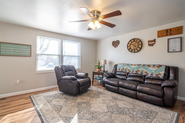 living room featuring visible vents, a ceiling fan, baseboards, and wood finished floors