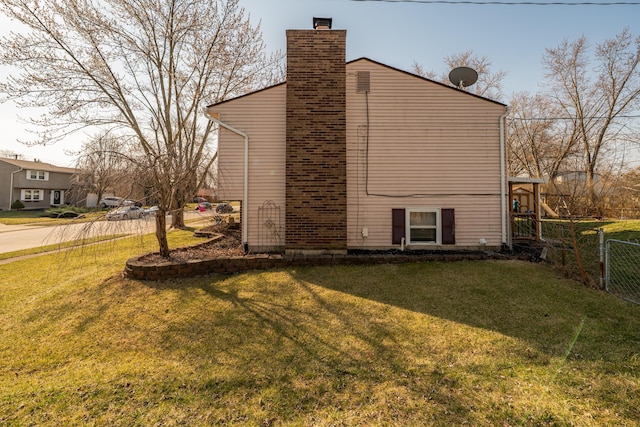 back of house featuring a yard, fence, and a chimney