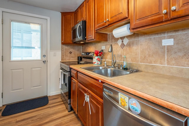 kitchen featuring light wood-style flooring, a sink, stainless steel appliances, light countertops, and brown cabinets