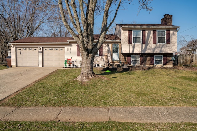 tri-level home featuring a garage, driveway, a front yard, and a chimney