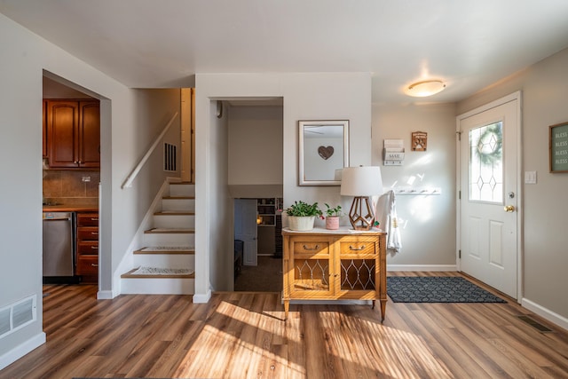 entrance foyer with stairway, baseboards, visible vents, and wood finished floors