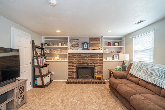 carpeted living area featuring a brick fireplace, built in shelves, recessed lighting, and visible vents