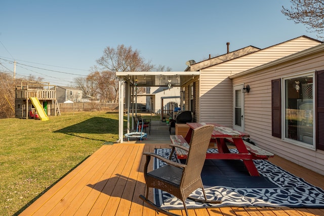 wooden terrace featuring a yard, a playground, and fence