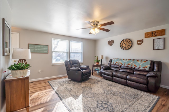 living area featuring light wood-style flooring, a ceiling fan, and baseboards