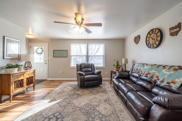 living area with baseboards, light wood finished floors, and ceiling fan