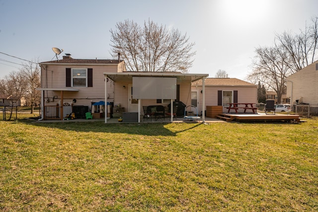 back of house with a deck, a patio, fence, a yard, and a chimney