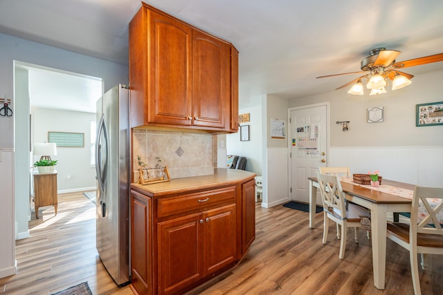 kitchen with light wood finished floors, brown cabinets, tasteful backsplash, and freestanding refrigerator