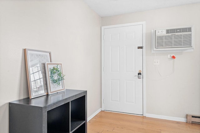 foyer entrance with light wood-style floors, an AC wall unit, a baseboard heating unit, and baseboards