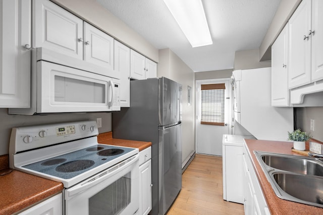 kitchen featuring a baseboard heating unit, white appliances, white cabinets, and a sink