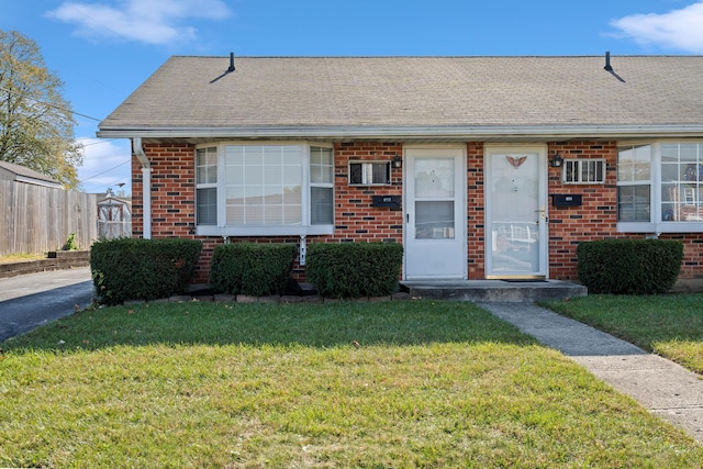 bungalow-style home featuring brick siding, a front lawn, and fence