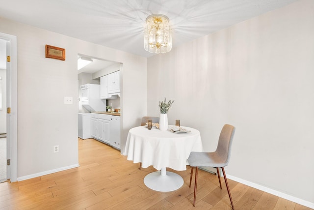 dining room with baseboards, a chandelier, and light wood-style floors