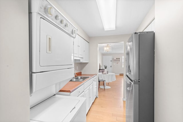 kitchen featuring light countertops, stacked washing maching and dryer, freestanding refrigerator, and white cabinets