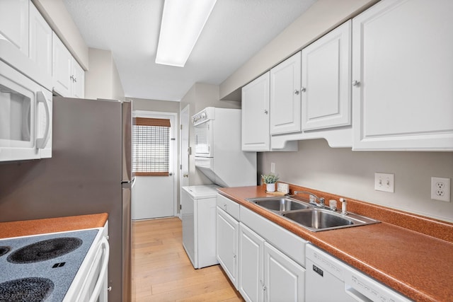 kitchen featuring white appliances, white cabinetry, a sink, and light wood finished floors