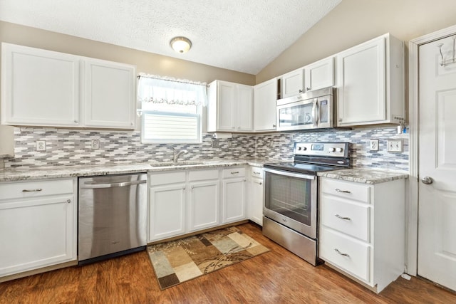 kitchen featuring white cabinets, vaulted ceiling, appliances with stainless steel finishes, and a sink