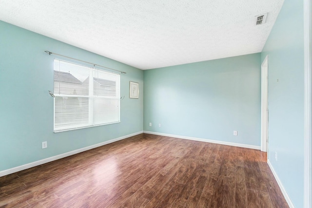 empty room with wood finished floors, visible vents, and a textured ceiling