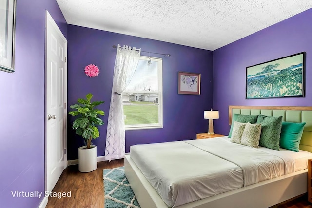 bedroom with wood finished floors, a textured ceiling, and baseboards