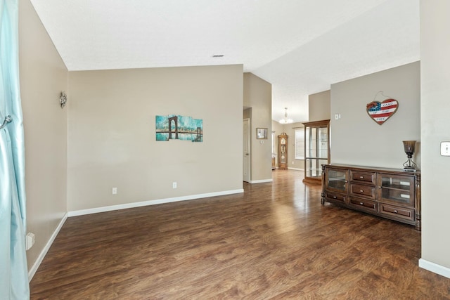 interior space featuring lofted ceiling, baseboards, and wood finished floors