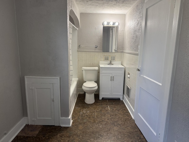 full bathroom with tile walls, vanity, a textured ceiling, shower / washtub combination, and toilet