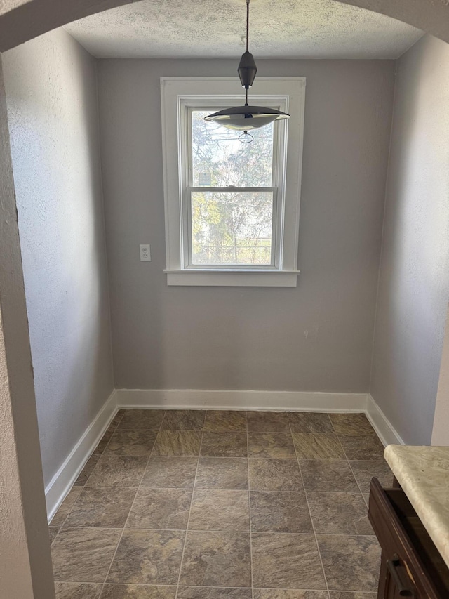 unfurnished dining area featuring a textured ceiling