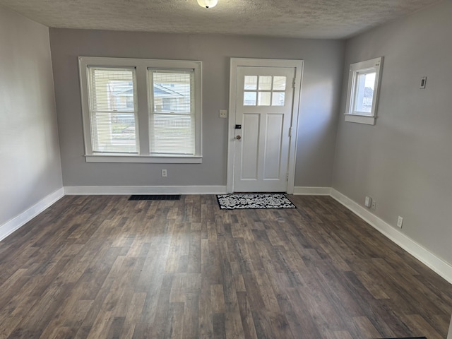 entrance foyer with dark wood-type flooring and a textured ceiling