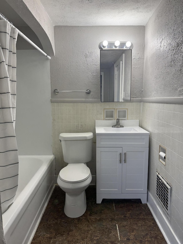 full bathroom featuring shower / bath combo with shower curtain, vanity, toilet, and a textured ceiling