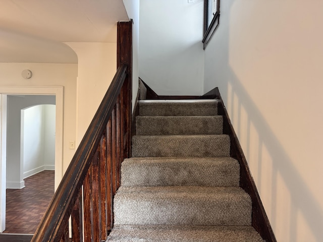 stairway featuring parquet flooring