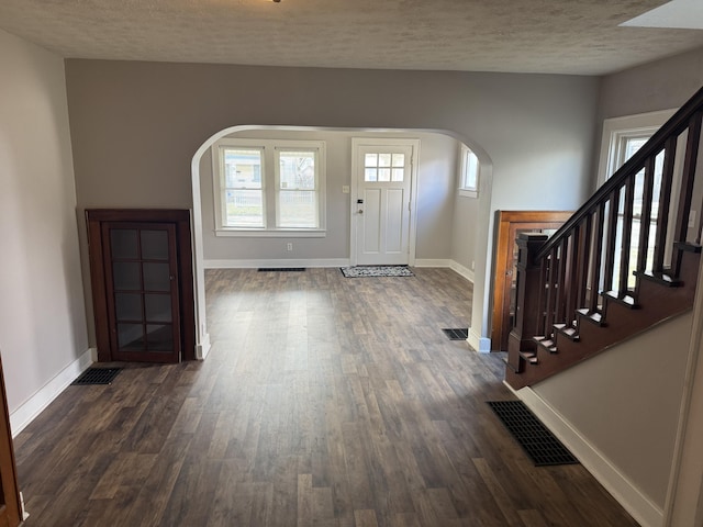 foyer entrance with dark hardwood / wood-style floors and a textured ceiling