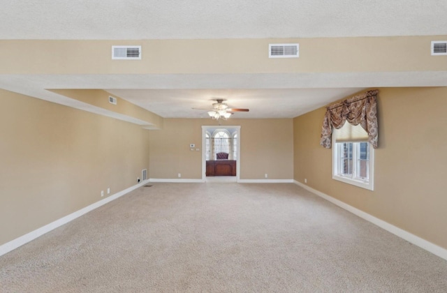 carpeted spare room with visible vents, a textured ceiling, and baseboards