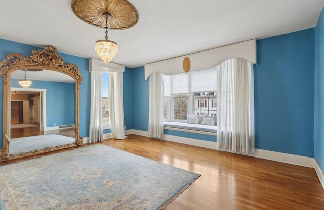 spare room featuring wood finished floors, baseboards, and an inviting chandelier