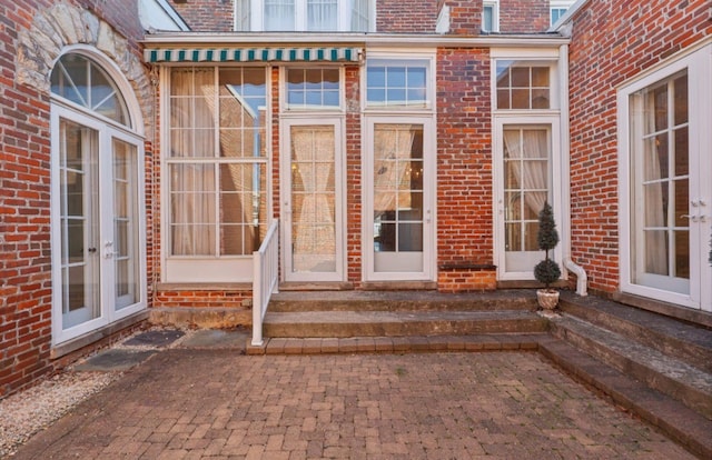 doorway to property featuring a patio, french doors, and brick siding