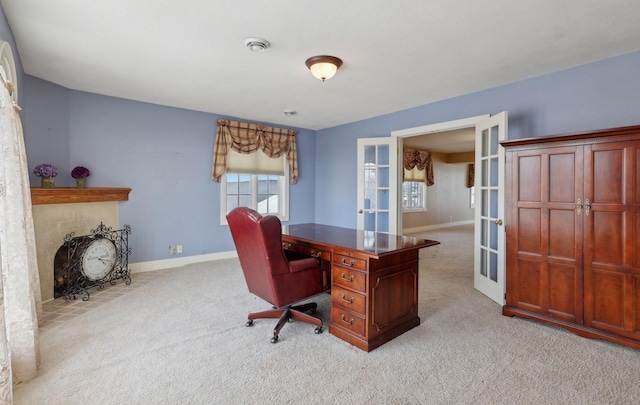 office area featuring french doors, light colored carpet, a fireplace, and baseboards