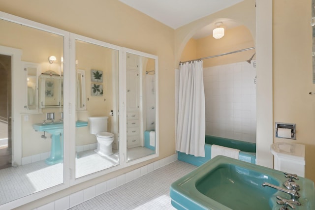 full bathroom with toilet, baseboards, a sink, and tile patterned floors