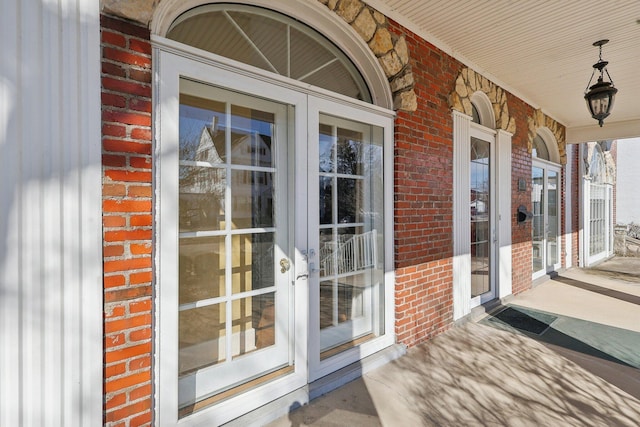 property entrance featuring french doors and brick siding