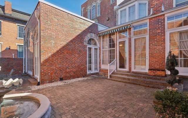 back of house with entry steps, a patio, and brick siding