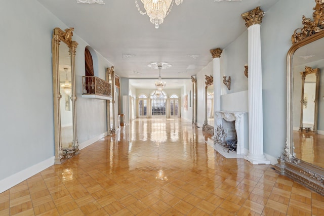 unfurnished living room with an inviting chandelier, a high end fireplace, and ornate columns