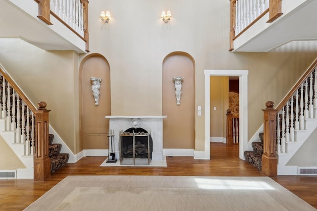 unfurnished living room featuring visible vents, a fireplace, baseboards, and wood finished floors