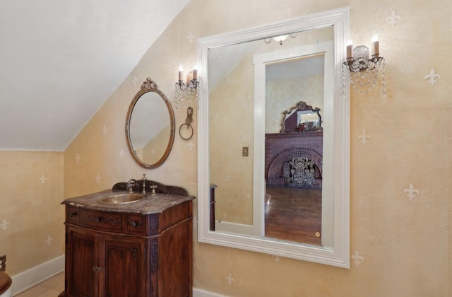 bathroom featuring lofted ceiling, a fireplace, and vanity