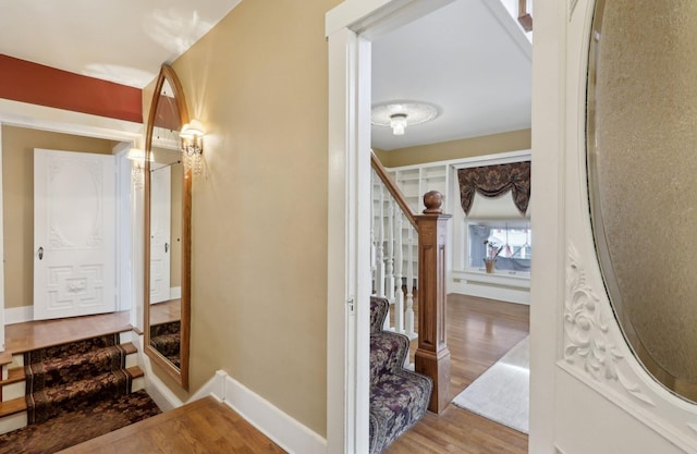 corridor featuring stairway, baseboards, and wood finished floors