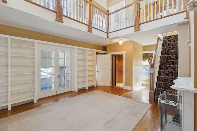 interior space featuring a towering ceiling, stairs, baseboards, and wood finished floors