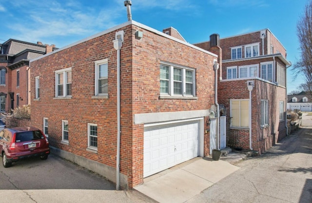 exterior space featuring driveway, a garage, and brick siding