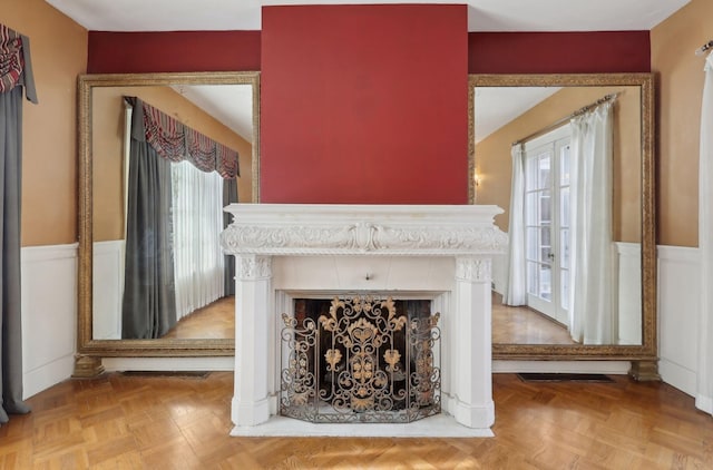 room details featuring a wainscoted wall, a tile fireplace, and visible vents