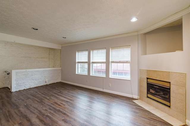 unfurnished living room featuring dark wood-type flooring, a tile fireplace, a textured ceiling, and baseboards