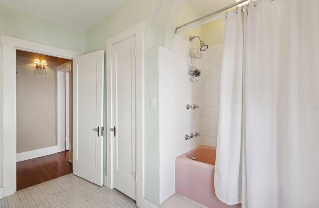 bathroom with shower / bathtub combination with curtain, baseboards, and tile patterned flooring