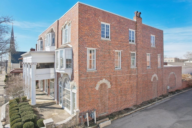 view of side of property with a chimney and brick siding