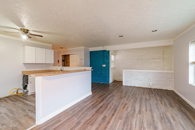 kitchen with a peninsula, a sink, white cabinetry, light wood-style floors, and light countertops