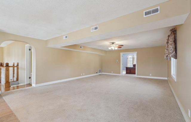 unfurnished room with ceiling fan, baseboards, visible vents, and arched walkways